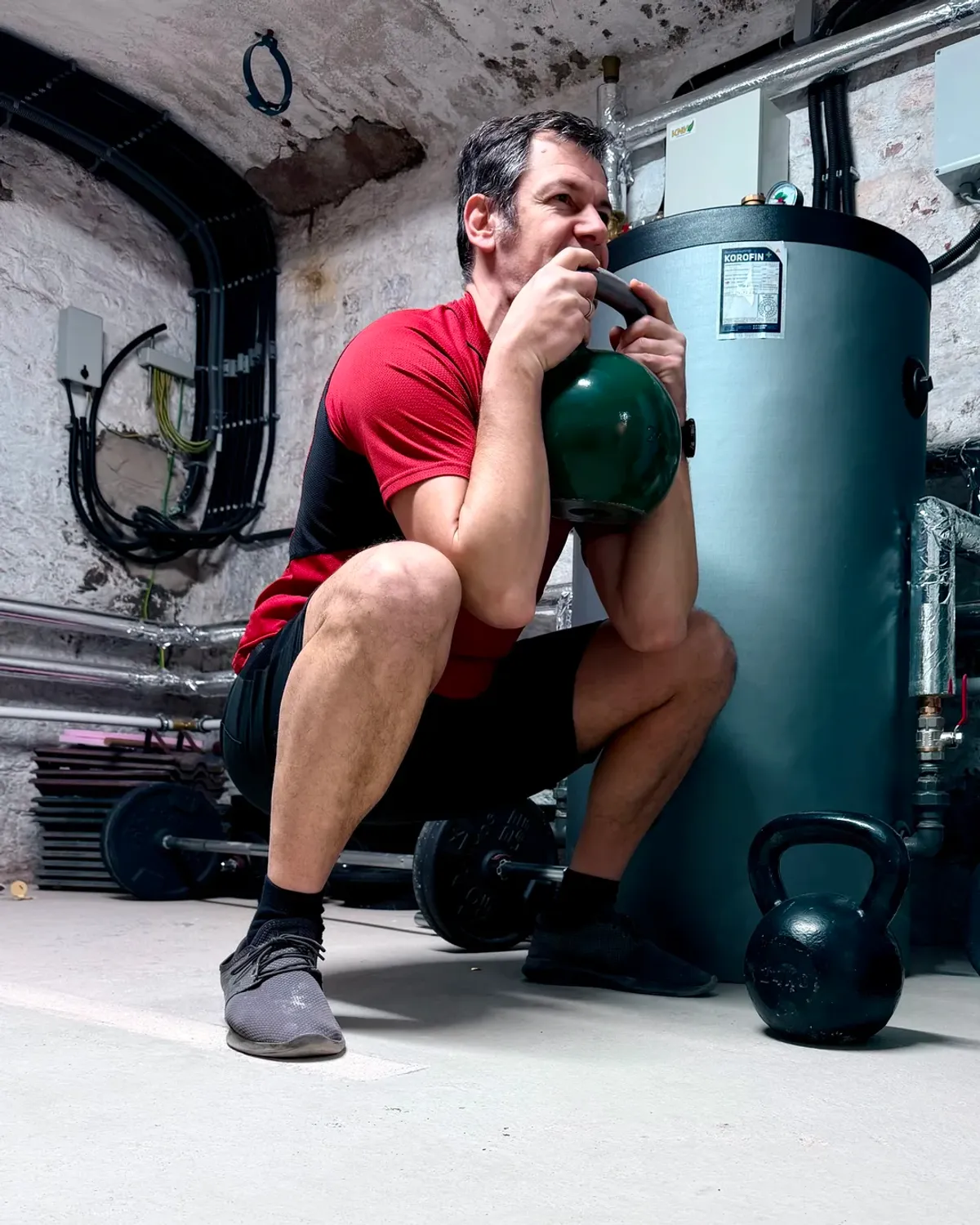 Me performing a kettlebell goblet squat in my workout dungeon